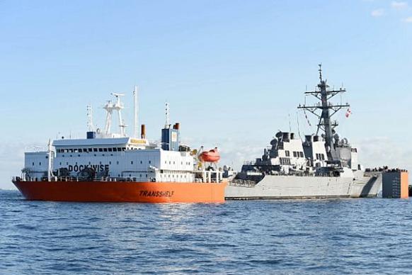 Погрузка американского эсминца USS Fitzgerald (DDG 62), типа  Arleigh Burke, на тяжелую транспортную баржу MV Transshelf, которая доставит его в Pascagoula, шт. Миссисипи, для ремонта после столкновения, фото сделано 24 ноября 2017 года в Токийском заливе, Япония